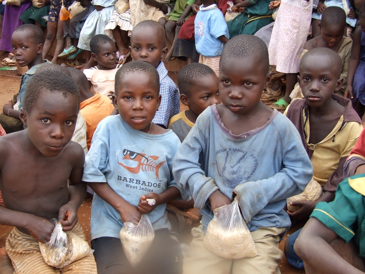 Young children seated together holding small bags of food support